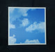 Framed photograph of a blue sky with white clouds on a black background